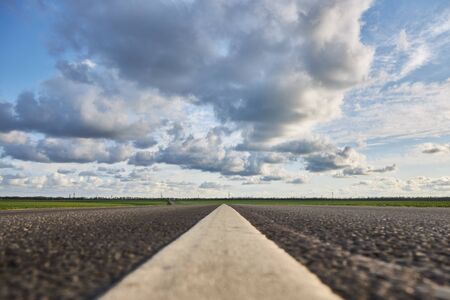 Empty asphalt road on a background of beautiful cloudy sky, close-up.の写真素材