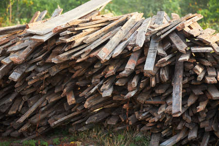 Pile of old wooden planks on green forest backgroundの写真素材