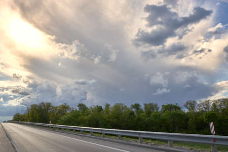 Empty highway asphalt against the background of cumulus clouds at sunsetの写真素材