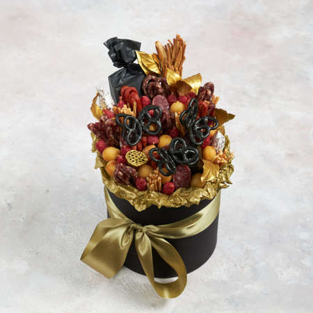 Round box filled with various types of sausages, cheese, decorated with golden paperの写真素材