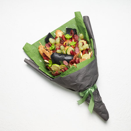 Gift to a man in the form of a bouquet of sausage, cheese, bread, decorated with rosemary, lemon and grapesの写真素材