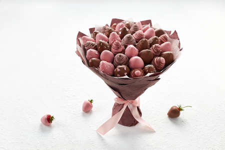 Sweet bouquet of strawberries covered with brown and pink chocolate on a white backgroundの写真素材