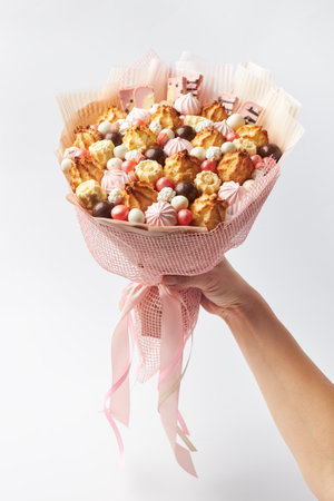 Funny sweet bouquet of cookies, marshmallows and chocolates in a female handの写真素材