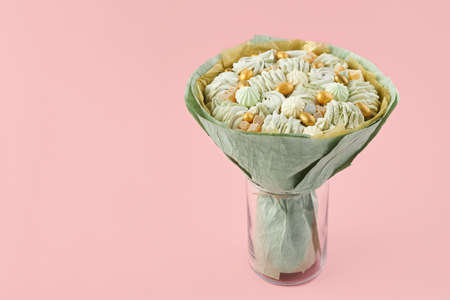 Unique bouquet of handmade marshmallows wrapped in green paper standing in a vase on a pink background, copy spaceの写真素材