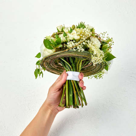 Wedding bouquet created on a frame of green branches in a hand of womanの写真素材