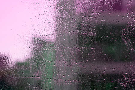 Wet window glass with raindrops and colorful abstract shapesの写真素材
