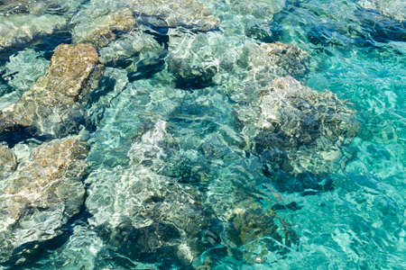 Transparent turquoise sea water and big rocks in sunlightの写真素材