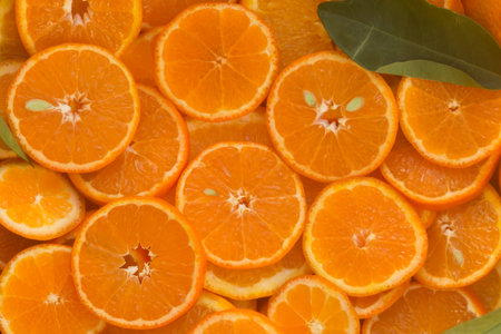 Close-up of round unpeeled orange slices with a few seeds and green leaf