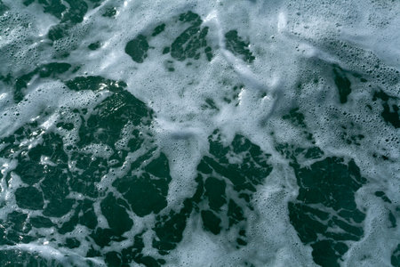Close-up of white foam and small bubbles on green sea water surfaceの写真素材