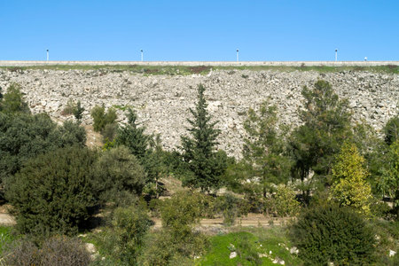 Embarkment dam with green trees nearby and blue sky aboveの写真素材