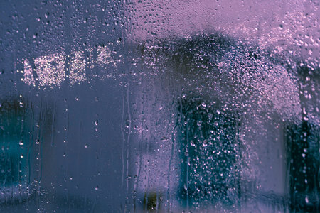 Texture of wet window glass with water drops, blurred shapes and silhouettes
