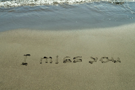 Phrase I Miss You written on beach sand