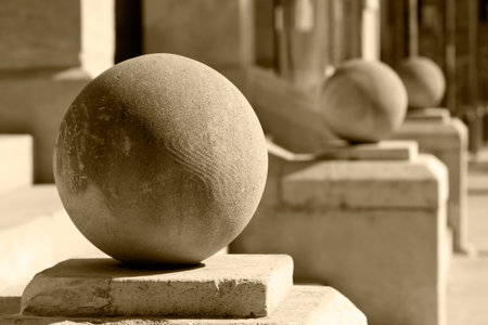Big stone balls in a row on pedestals in front of staircase