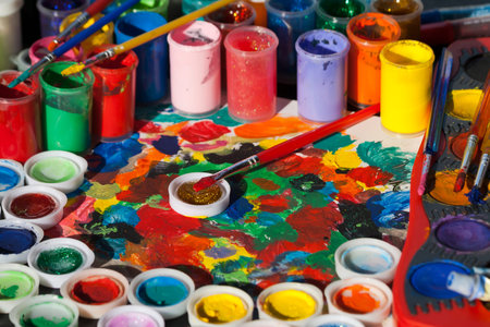 Lots of bright multi colored paints, a palette and paintbrushesの写真素材