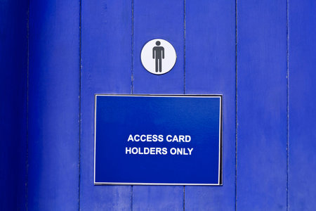 Close-up of a blue wooden public toilet door with a restroom sign and a noticeの写真素材