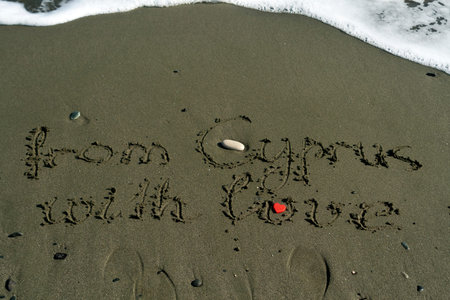 Words From Cyprus With Love written on sandy beach next to sea wave