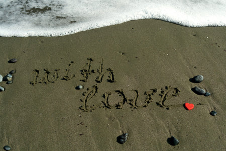Words With Love written on beach sand beside sea wave