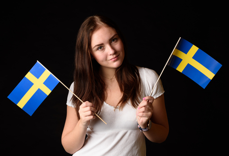 Girl with two Swedish flags isolated on black backgroundの写真素材