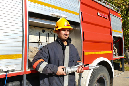 Firefighter in full gear / Fireman stands in front of a fire truck