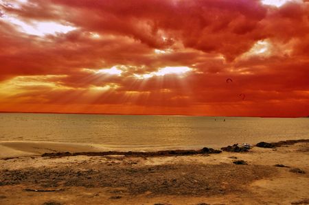 view to a bay with the sun rays behing the clouds and kitesurfersの写真素材