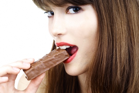 beautiful girl biting a bar of chocolate in a sexy wayの写真素材
