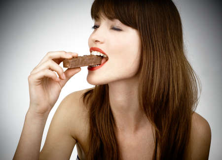beautiful girl biting a bar of chocolate in a sexy wayの写真素材