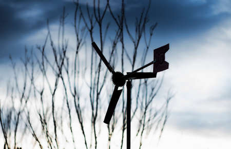 home made wind propellers with tree branches on the foregroundの写真素材