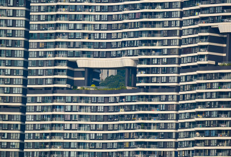 A contemporary high rise building features a large open section with trees, contrasting its grid...
