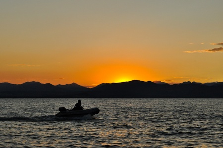 A man in a rubber motor boat at duskの写真素材