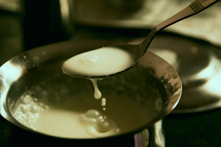White sauce being mixed in a green bowl with a spoon, ready to be served.