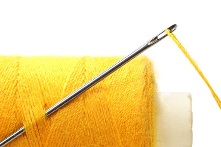 A spool of thread and a needle isolated on a white background 