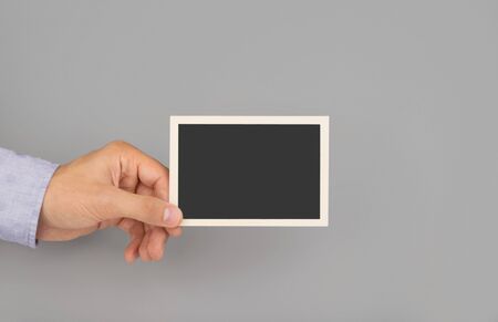hand holding photo frame grey backgroundの写真素材