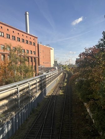 Berlin Germany October 2025 Railway tracks beside red brick industrial building under clear blue skyの写真素材