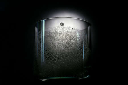 Close-up of foam structure on a glass surface. Glass on a black background. Foam bubble from soap or shampoo washing isolated on a glass. Creative photographyの写真素材