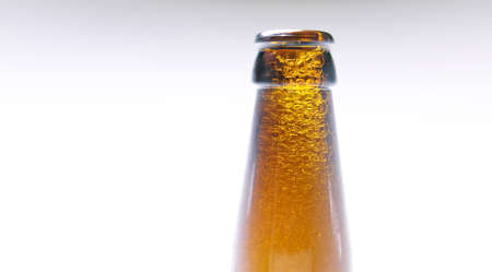 Close-up of beer foam, long neck beer bottle, alcoholic beverage white backgroundの写真素材