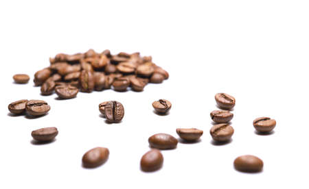 Selective focus scattered beans of medium roast coffee on a white background. Arabica roast coffee beans. Toning drink, natural energetic. Beans closeup, morning aroma. Space for text.の写真素材