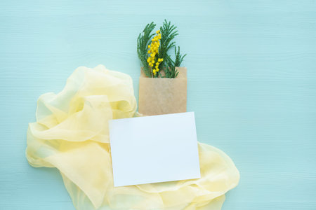 Mimosa brunch in brown envelope bag in blue on a background of yellow silk with white blank card for...