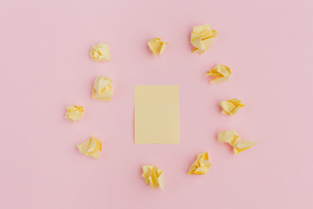 a bunch of crumpled yellow stickers of paper, scattered on a pink background, in the center of a...