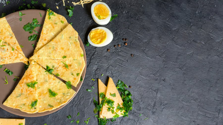 pancake with cheese, herbs and egg for Shrovetide. cheese tortilla is cut into pieces and sprinkled with cheese . on a dark background, the top view. space for text.の写真素材