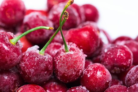 group of frozen cherries on a white background in a white plate. . close up. ice crystals on the fruit. vertical photo of the top view . macro.の写真素材
