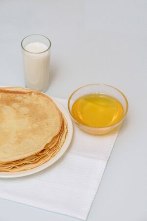 Maslenitsa is a holiday at the end of February . pancakes with sour cream, honey and milk on a light background. close up. blini. space for textの写真素材