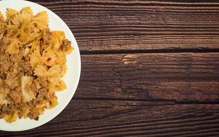 fresh delicious nutritious pasta with meat on a wooden background . half of the plate in the photo. the view from the top. photo for banner, place for text . close up.の写真素材