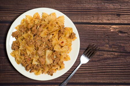 pasta with meat on a wooden background with a fork in hand. photo for banner, place for text.の写真素材