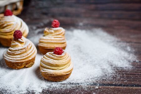 Modern trend baking 2020-cruffins puff muffin , a mixture of croissants and muffins. On a dark wooden table sprinkled with powdered sugar. Place to copy, view from above.の写真素材