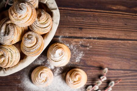 Delicious modern cruffins are made from puff croissants in the form of a muffin. cruffins with a wooden basket on a dark wooden background, sprinkled with powdered sugar and raspberries. Copy space.の写真素材
