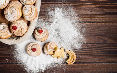 Delicious cruffins are made from layered croissants in the shape of a bun. muffins on a dark wooden background, sprinkled with powdered sugar and raspberries. Copy space, top viewの写真素材