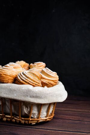 Modern fashion pastries in 2020-cruffins, a mix of croissants and muffins. On a dark table, sprinkled with powdered sugar. the view from the top. in a wooden basket. close up.の写真素材
