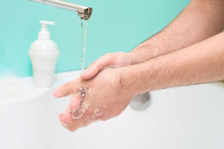 washing and disinfecting hands from germs and viruses with soap and water jet on a blue background. coronavirus pandemic, personal health protectionの写真素材