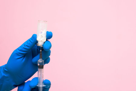 virus vaccine in hand in a medical glove against coronavirus on a blue background. space for text....