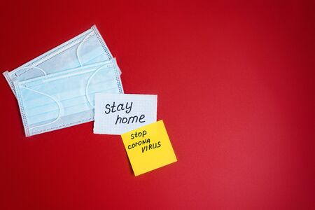 text-coronavirus, stay at home, office at home written on yellow sheets of paper by hand. the view from the top. Mask on a red background. the concept of a pandemic, self-isolation. 2019-nCov.の写真素材